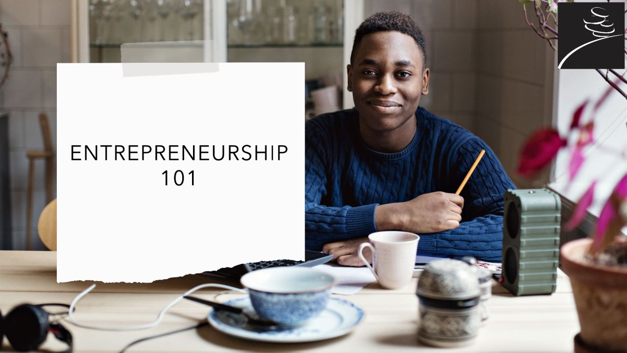 Entrepreneur, dark skinned young man sitting on a table facing the camera